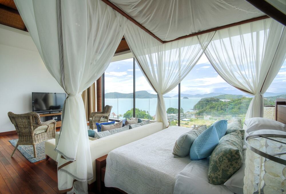 A luxurious hotel bedroom with a sea view.