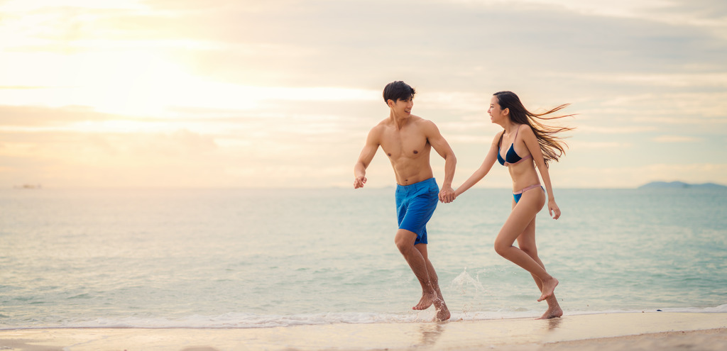 A happy couple running on a beach in Phuket